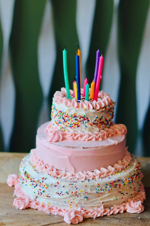 a birthday cake with multiple layers covered in pink frosting