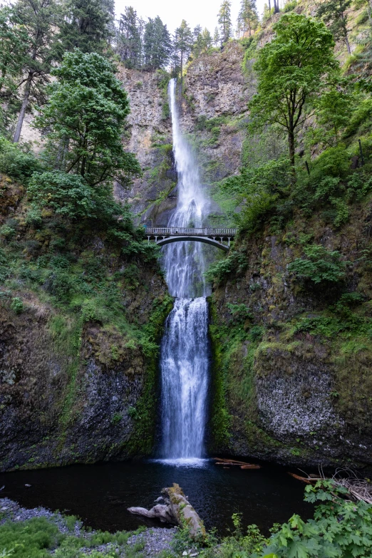 the tall waterfall is about to fall down into the river