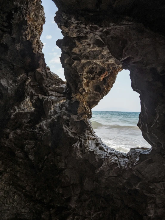 view of the ocean through a cave at the beach