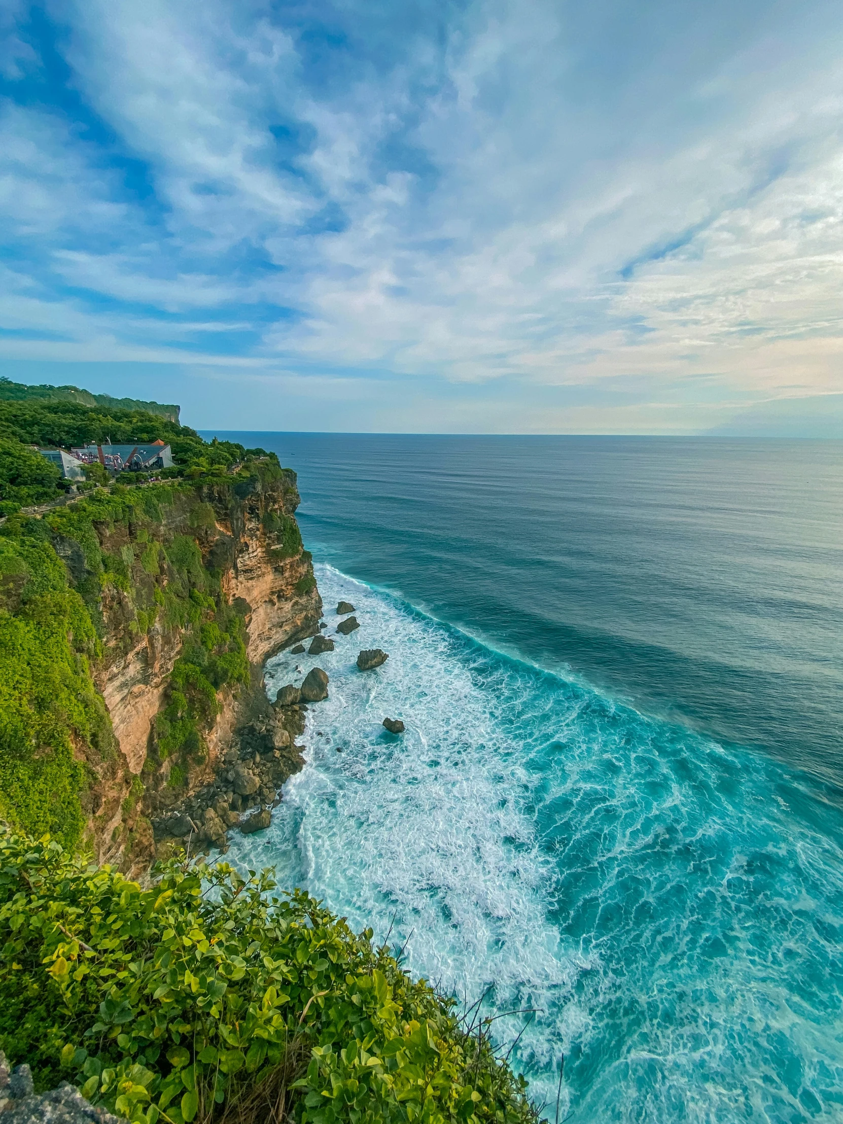 a view of a shoreline, with the ocean, clouds and house