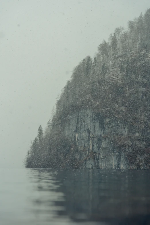 a lake covered in rain next to some trees