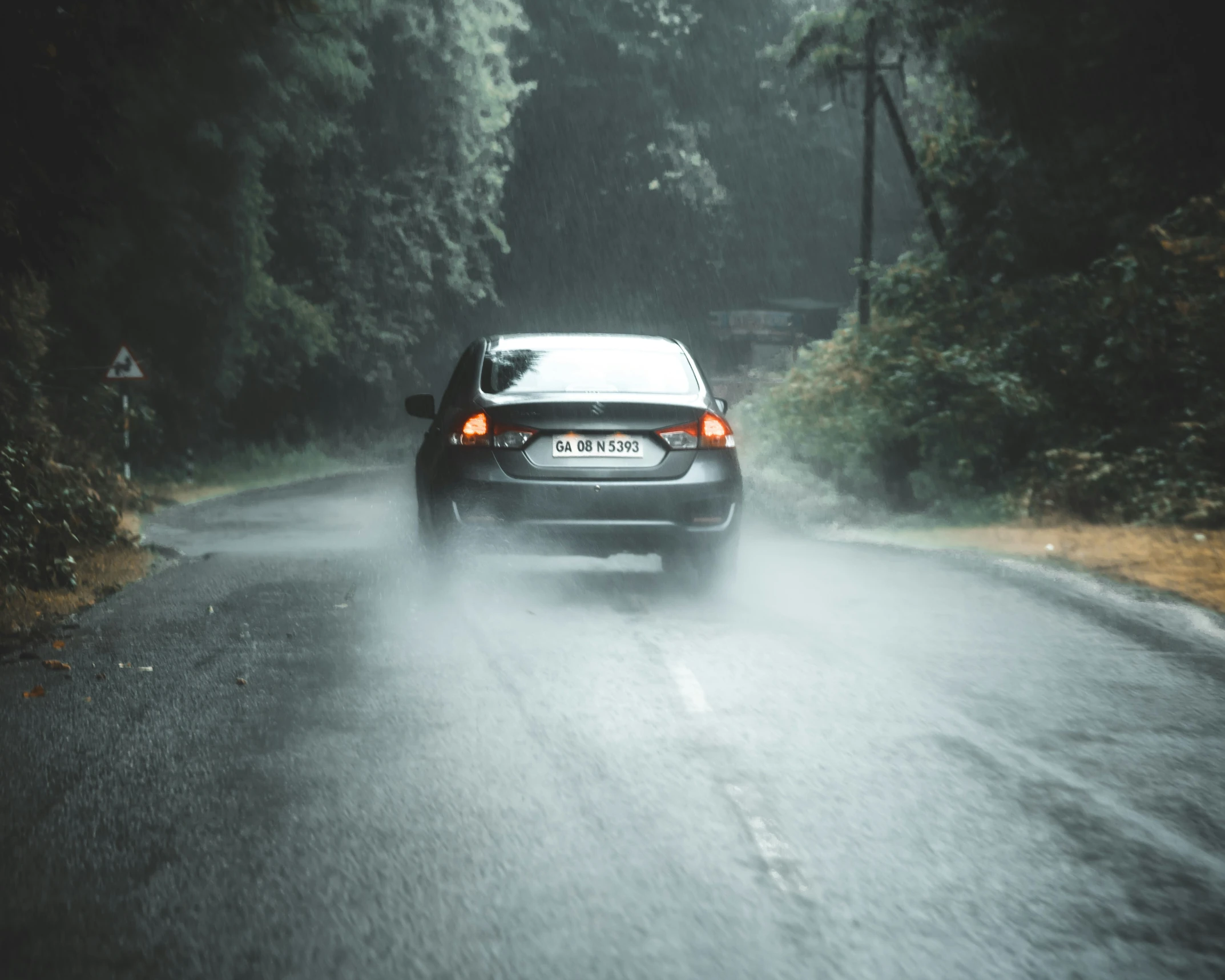 a car driving on a rainy road near trees