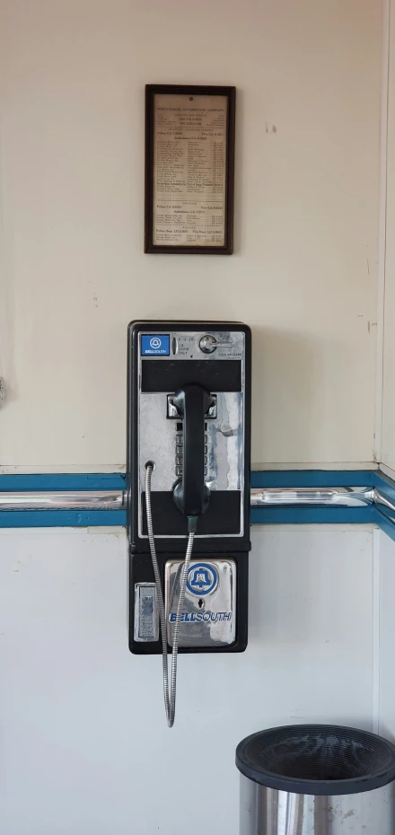 a cellphone is hanging from a wall next to a trash can