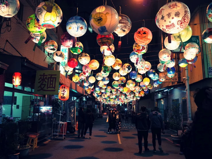 a number of people in an open area with lighted lanterns