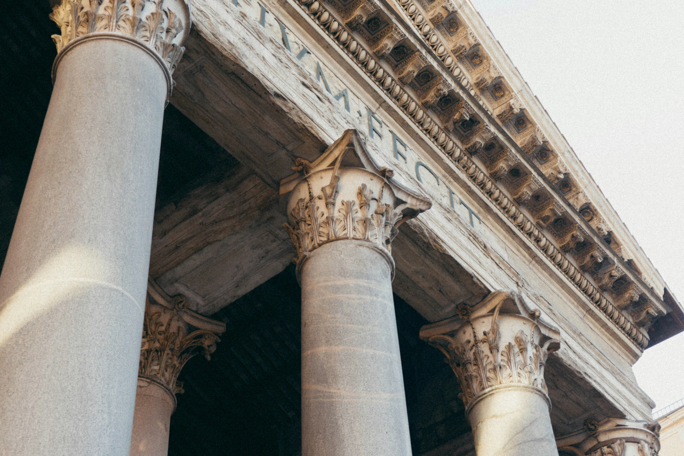 three large white pillars with words painted on them