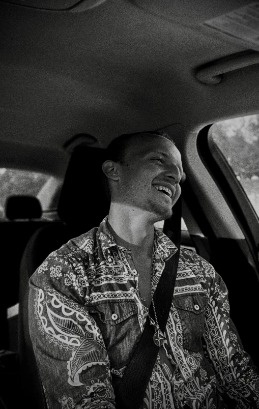 a man wearing a tie sitting in a car smiling