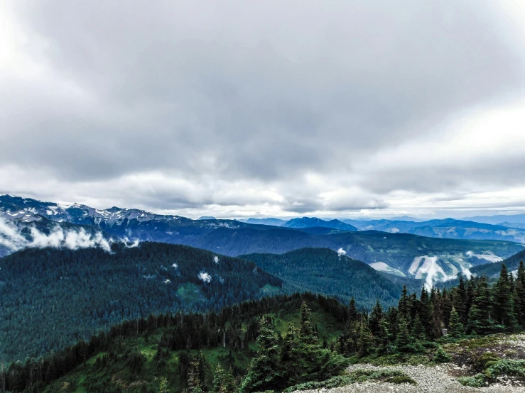 a mountain with a forest below and clouds