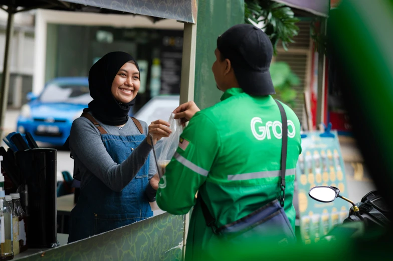 a man giving money to a woman in green