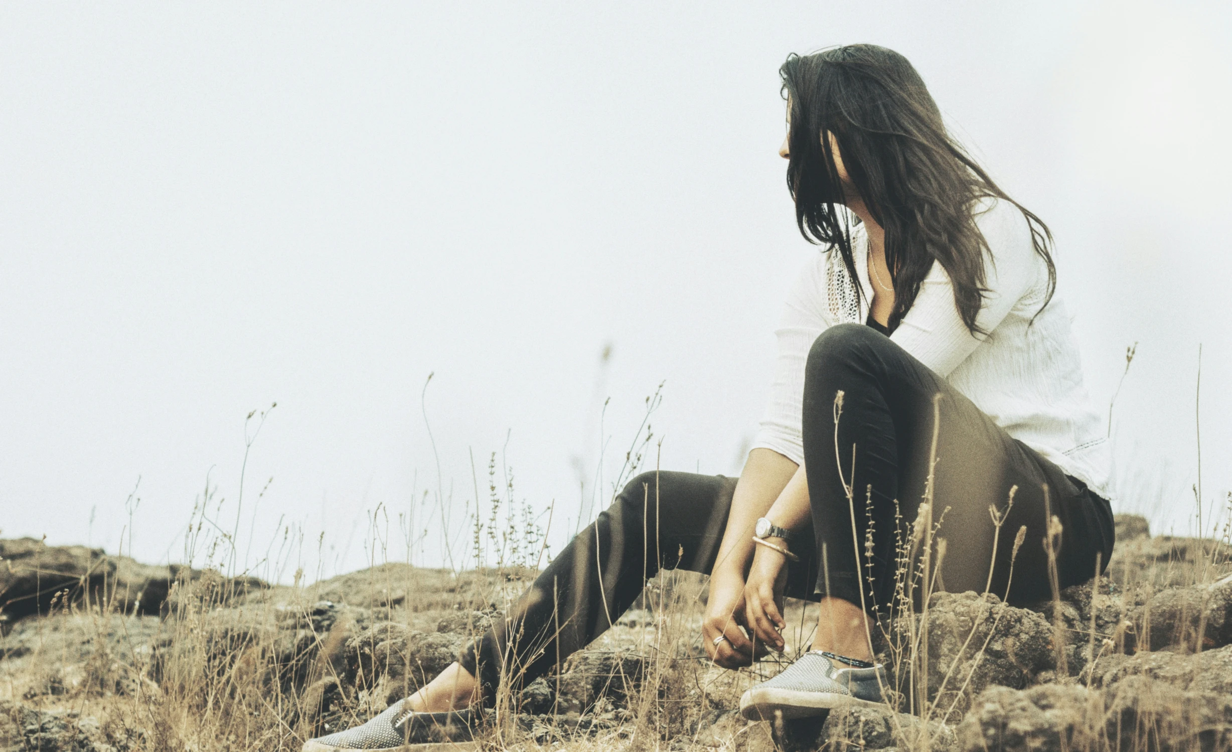 a girl sitting on a rock in the grass