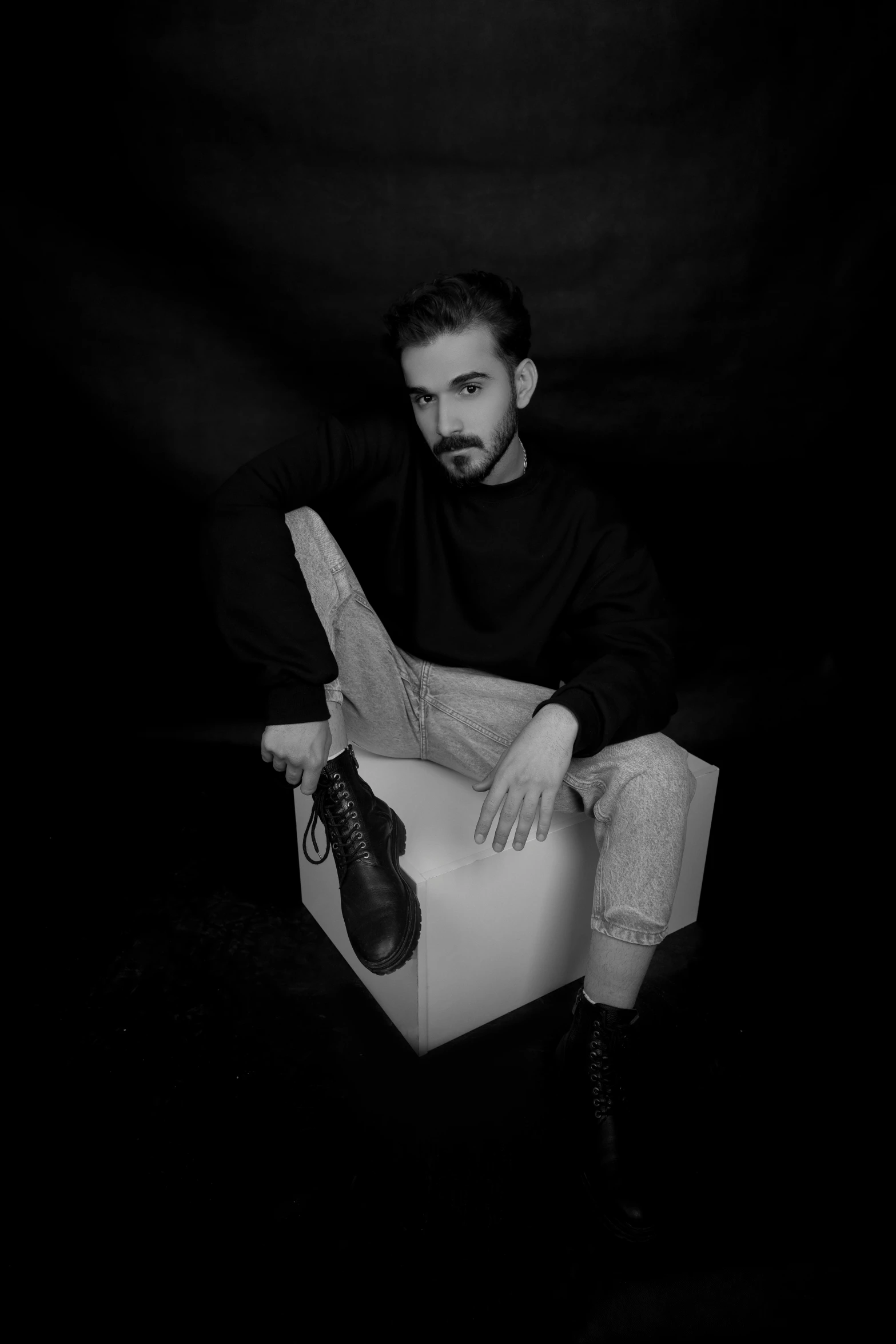 a man with his hand on his knee is sitting in a white box