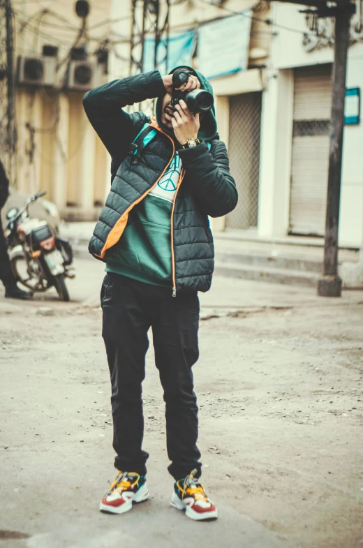 a person in a green jacket is standing near a bike