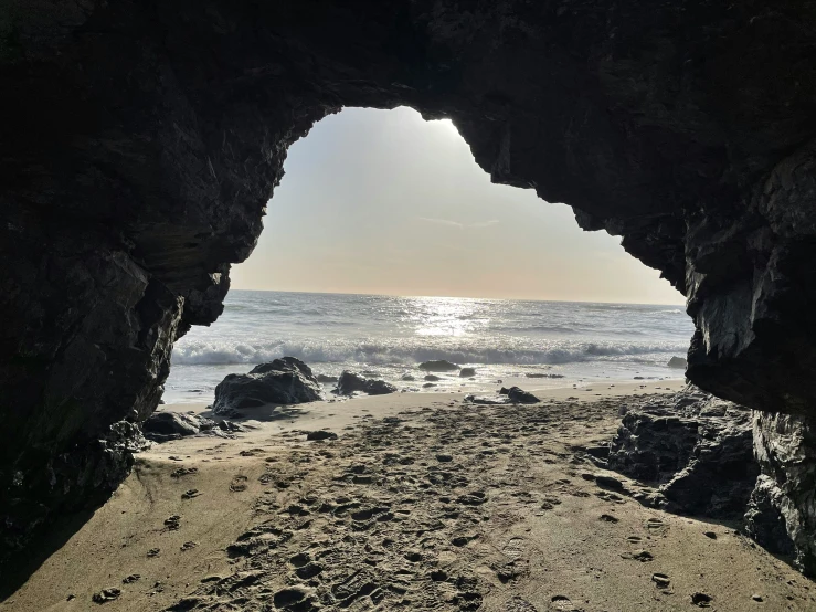 the sun is peeking out of an overhanging cave