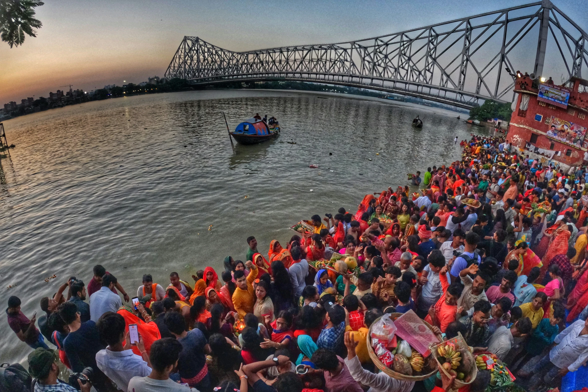 crowd of people gathered at waterfront area near bridge