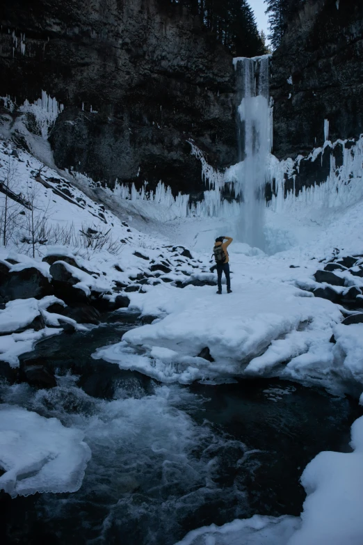 a man is in the snow near a small waterfall