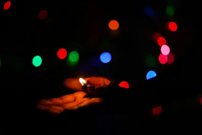 a person holding out a small lit candle in their hand