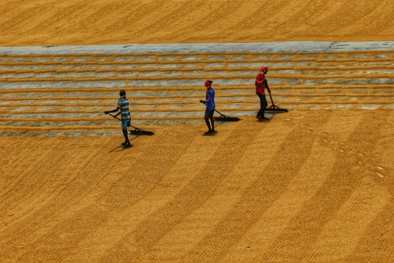 three men standing in a dirt field with a field line behind them