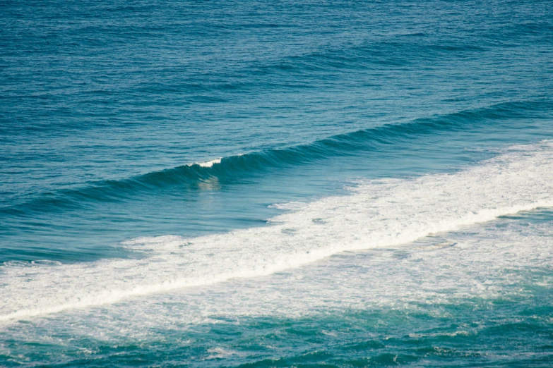 a person surfing on the ocean, with blue water