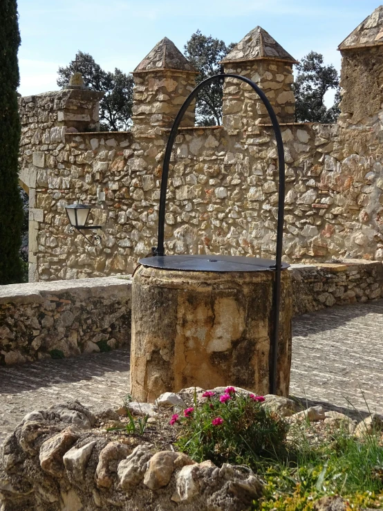 a stone structure with curved arches and a wrought iron stand in front of an old wall