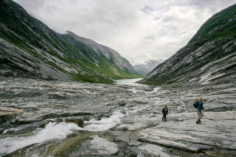 two people walking on rocks in a barren area