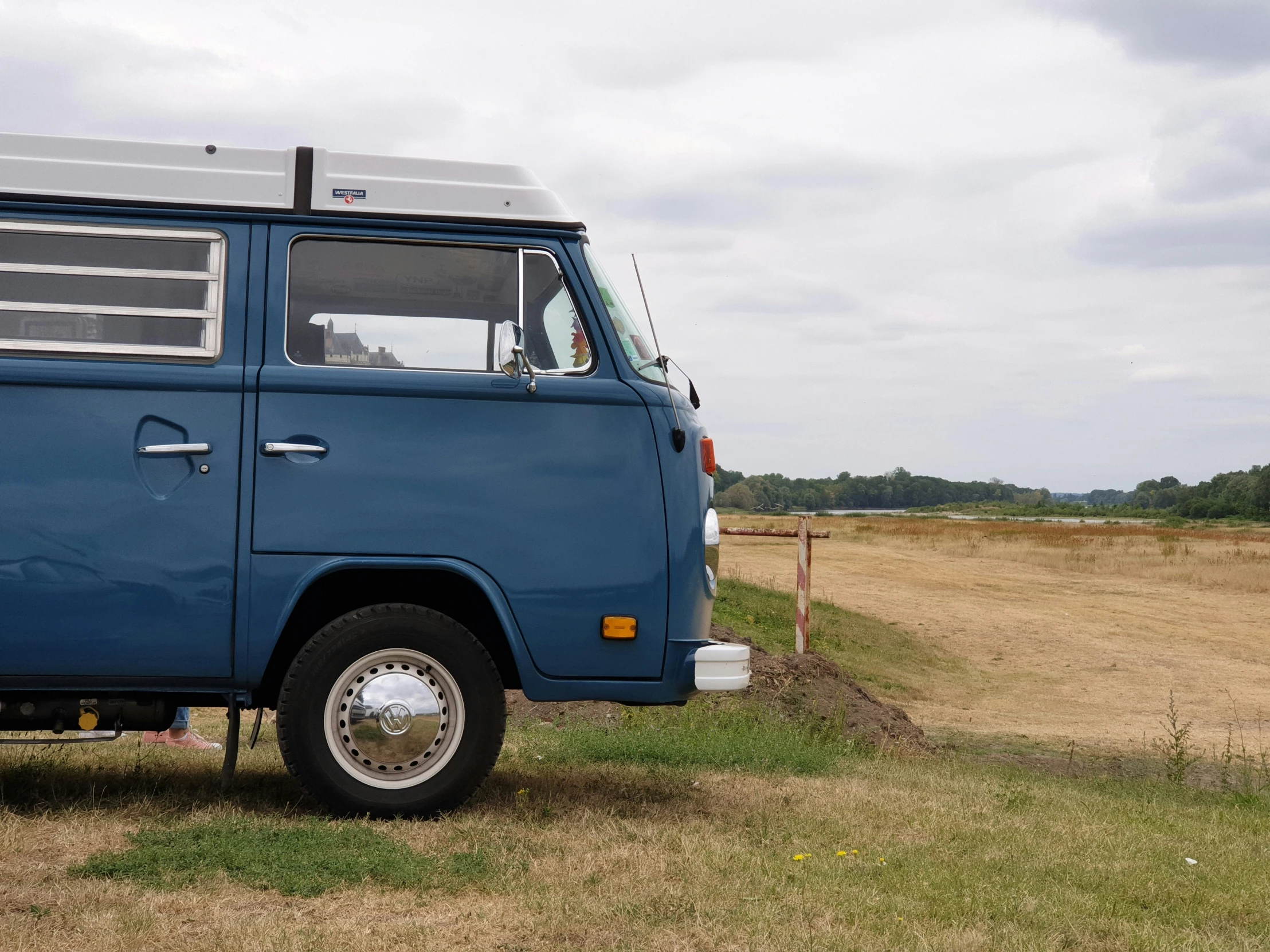 a blue van parked in a field with grass