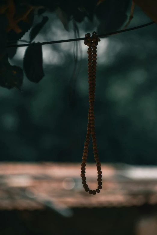 a rosary hangs on a rope in front of a wooden bench