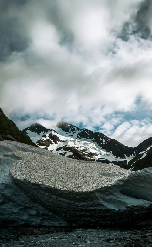 an iceberg is in front of some snowy mountains