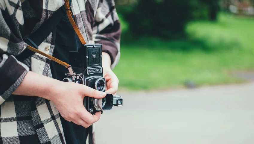 the person in plaid holds a camera outside