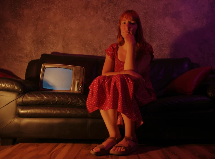 a little girl is sitting on a couch with a tv