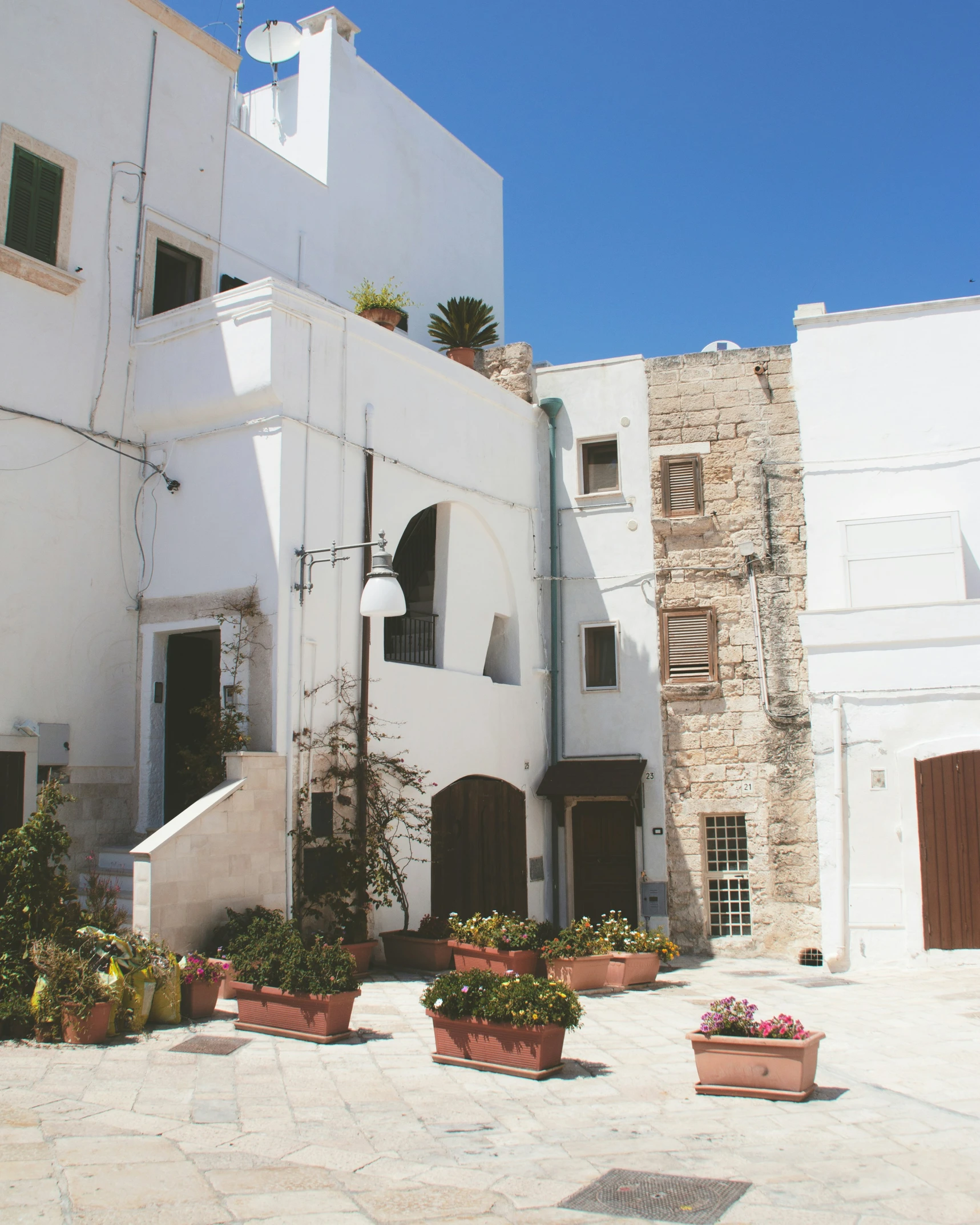 an alley with white houses and flowers on a sunny day