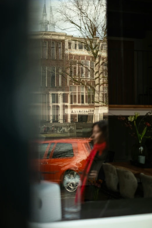 a woman looks out the window at a car parked on the street