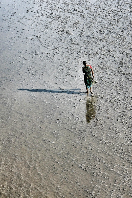 a man walking in the ocean carrying a surfboard