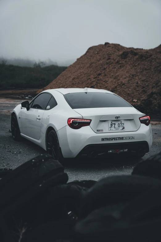 white toyota sports car is parked on a gravel road