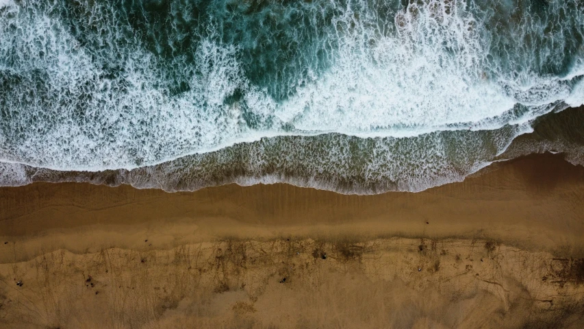 an aerial view shows the ocean waves and sand