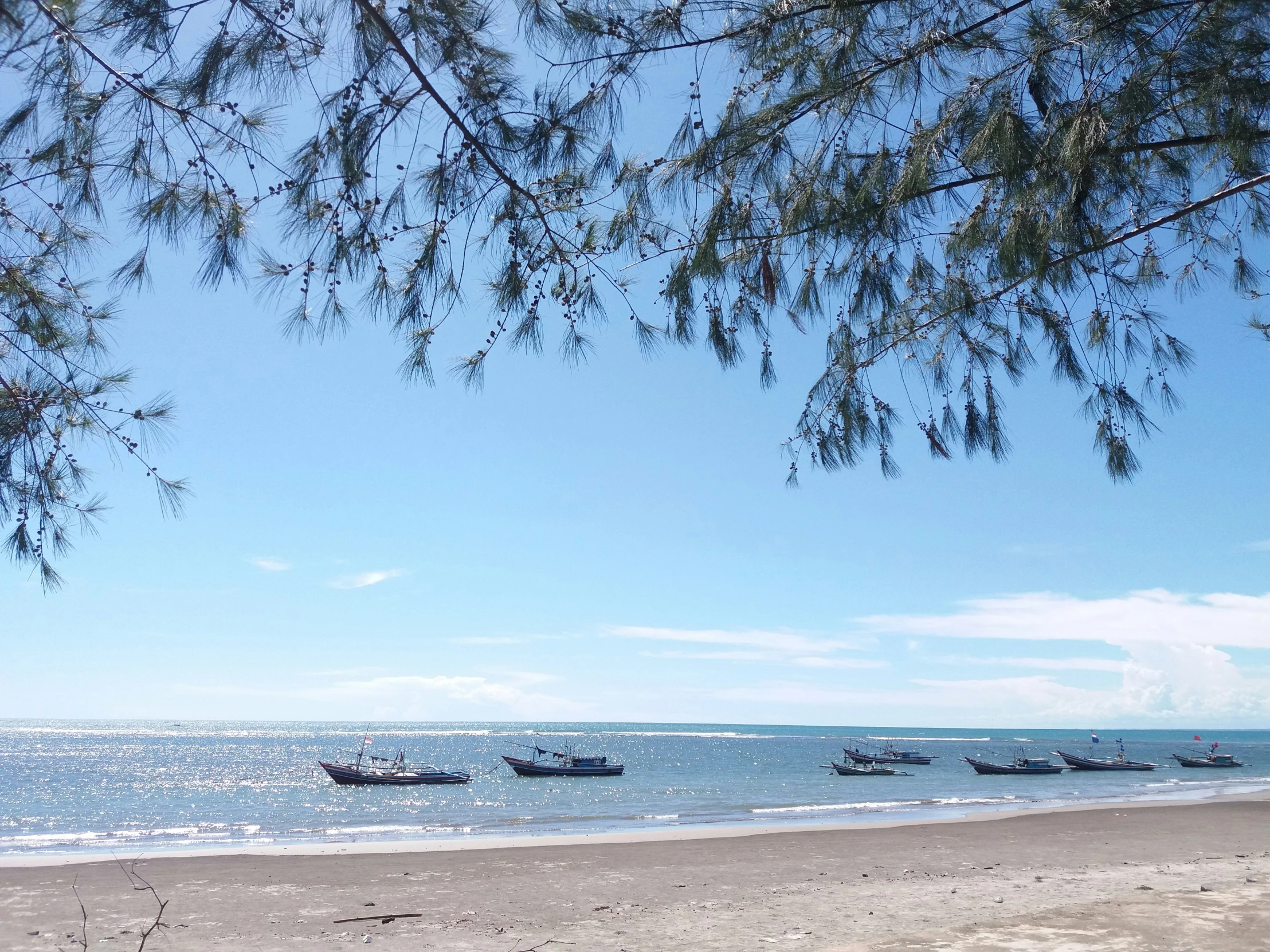 a beautiful blue ocean and some boats sitting on the beach