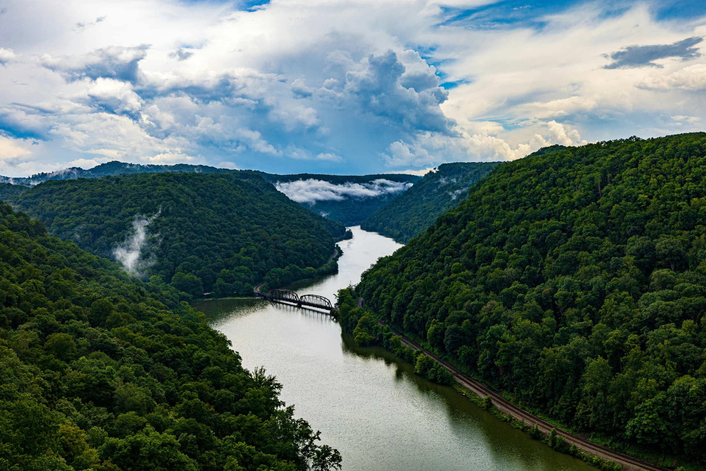 a river flows through a valley surrounded by green trees