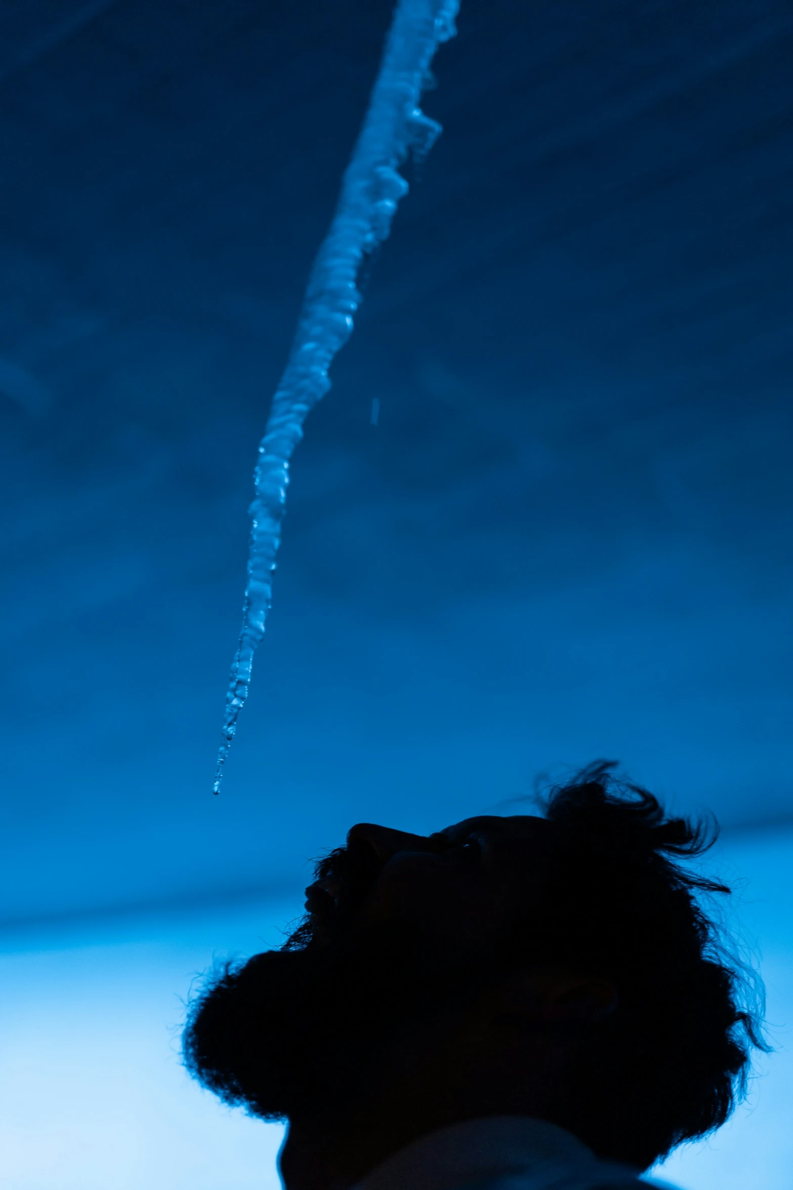 a person looks up to the sky as some ice crystals are in mid - air
