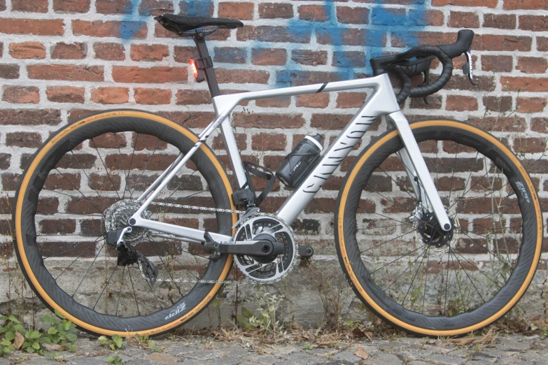 the front wheel of a silver bike is leaning against a brick wall