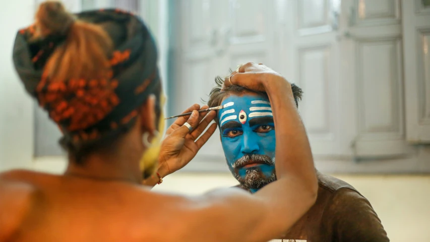 a woman wearing blue has a painted face on the man