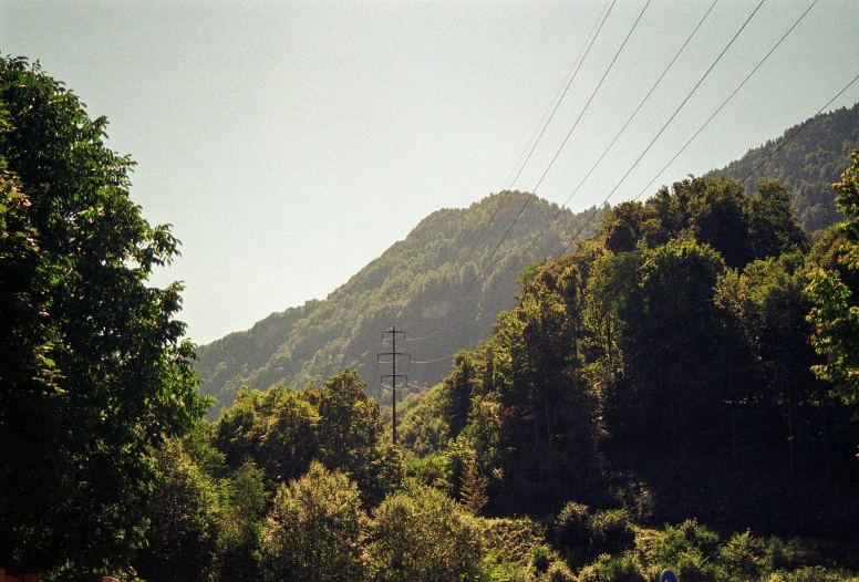 some power lines over a forest and hills