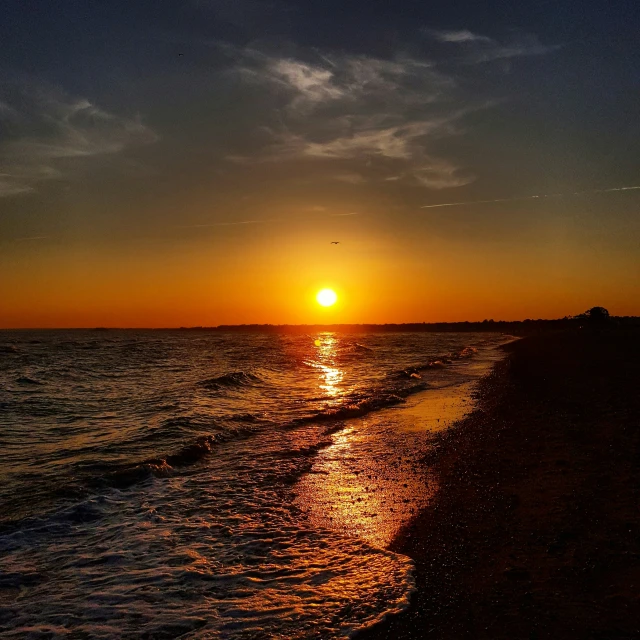 a large body of water with the sun setting