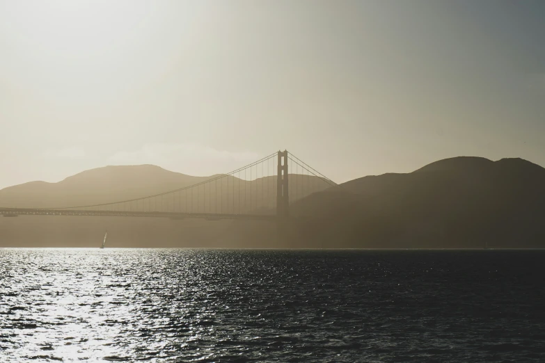 a golden gate bridge is silhouetted against the hazy sky