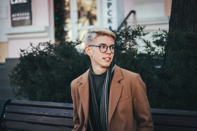 a young man wearing glasses and a suit standing on a sidewalk