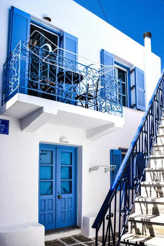 an all white house with blue doors and a spiral staircase