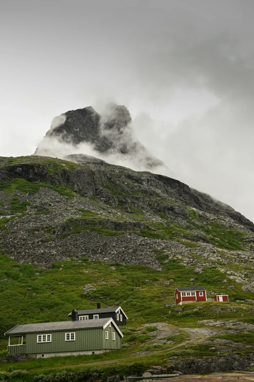 a mountain with three cabins below a thick, smoggy cloud