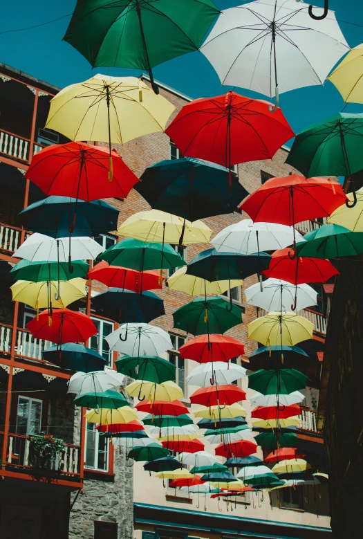 multicolored umbrellas floating in the air over a city street