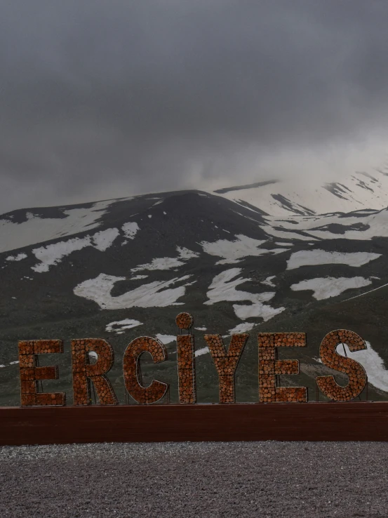a snowy mountain range covered in snow behind a red and brown sign