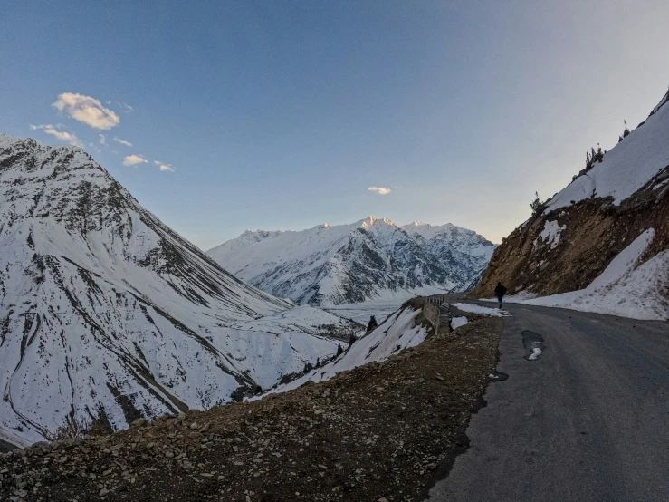 a long empty road between snowy mountains on the side