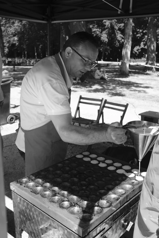 a man with glasses preparing cupcakes on top of a metal table