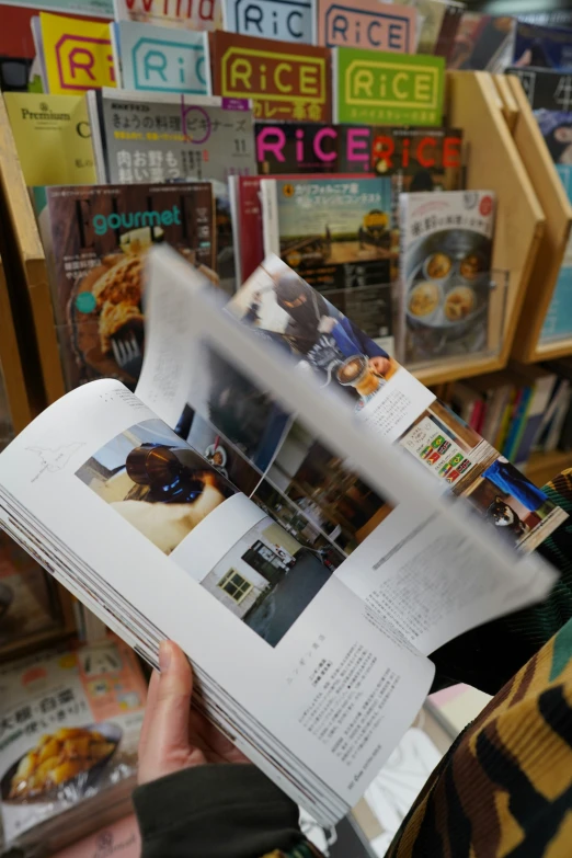 a person reading a newspaper and holding up one of their hands