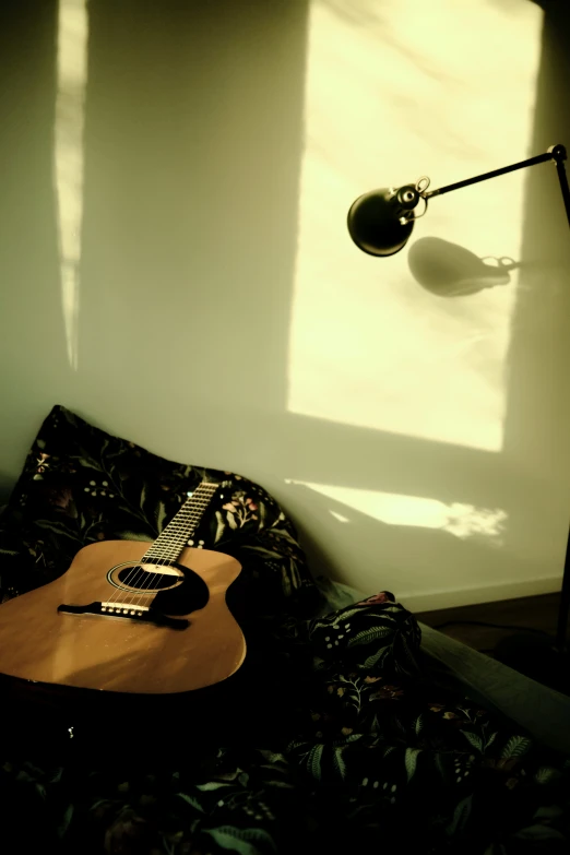 a guitar resting against a wall and the light from a spotlight